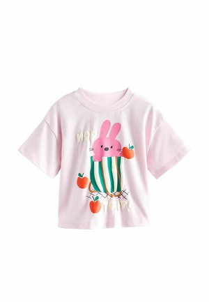 Hellrosa kurzärmeliges Hemd mit einem Design eines rosa Hasen in einem grün gestreiften Korb, umgeben von drei roten Äpfeln.