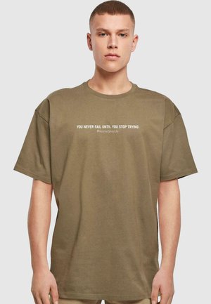 Oliven grøn t-shirt med korte ærmer, rund halsudskæring og trykt hvid tekst: "DU FEJLER ALDRIG, FØR DU STOPPER MED AT PRØVE #NeverGiveUp."