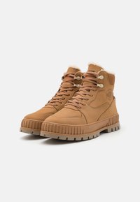 Bottes de cheville en cuir tan avec une semelle en caoutchouc texturée, fermeture à lacets et doublure en fausse fourrure au col. Présente une marque sur le côté.