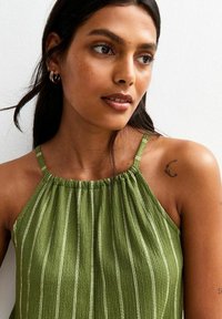 Top a halter verde, con texture, spalline sottili e righe bianche verticali, con scollatura arricciata e tessuto morbido e leggero.