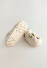Sabots beiges en caoutchouc, ornés d'patchs décoratifs d'un avocat vert, d'une fraise rose et d'une tranche de pain en dessin animé. Semelle texturée.