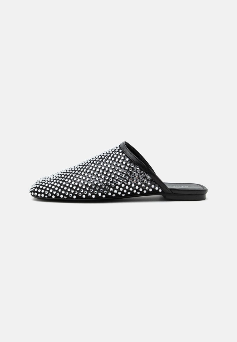 Chaussure plate noire à enfiler avec bout pointu, recouverte de clous argentés brillants disposés régulièrement, sur un fond gris clair uni.