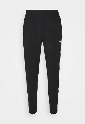 Schwarze Sporthosen mit elastischem Bund, tailliertem Schnitt und seitlichen Reißverschlusstaschen. Mit einem weißen Logo auf dem linken Oberschenkel.