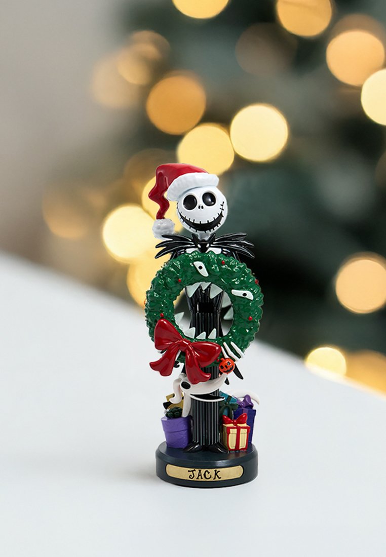 Figurita de Jack Skellington vistiendo un gorro de Santa y sosteniendo una corona verde con un lazo rojo, de pie sobre regalos con una placa que dice "Jack".
