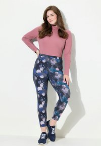 Leggings multicolori con un motivo a bolle nei colori blu navy, blu, rosa e grigio, abbinati a un top aderente a maniche lunghe rosa. Le scarpe sono blu navy.