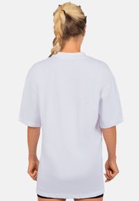 Witte oversized t-shirt met korte mouwen, soepele textuur, ronde halslijn en gestikte zoomdetails; geen zichtbare grafische elementen of patronen.