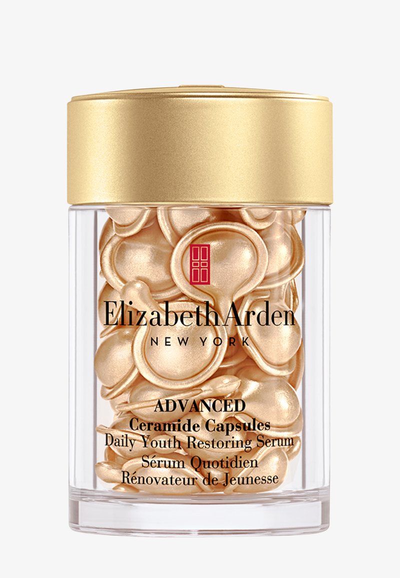Pot transparent avec couvercle doré contenant des capsules dorées en forme de larme étiquetées Elizabeth Arden Advanced Ceramide Capsules Daily Youth Restoring Serum.