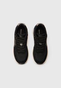 Melnas un baltas GANT sneakers ar auklām, skatoties no augšas uz baltas fona.