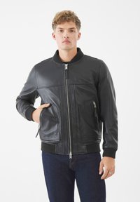 Chaqueta bomber de cuero negro con cuello acanalado, cremallera frontal y dos bolsillos laterales. Presenta una textura suave y un diseño estructurado.