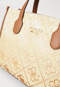 Tan handbag with a woven straw texture featuring a diamond pattern and embossed logo. Accented with brown leather handles.