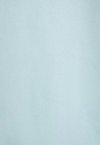 Tejido azul claro con una textura suave y un sutil patrón de acanalado, presentando un color uniforme y sin logotipos ni adornos visibles.