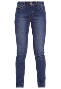 Tajta jeans i mörkblå denim, med en klassisk femfickorsdesign, framknappsstängning och subtila blekningar här och där.