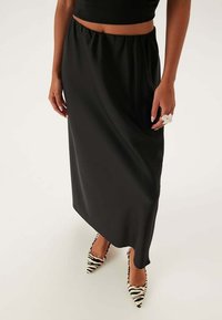 Sort satin maxi nederdel med elastisk talje, parret med spidse hæle med zebra-mønster. Glat tekstur, gulvlængde design.