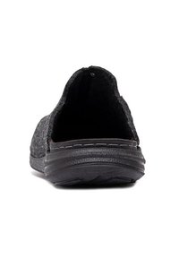 Tylny widok czarnego buta typu slip-on z teksturowaną podeszwą i miękką górą z materiału, na białym tle.