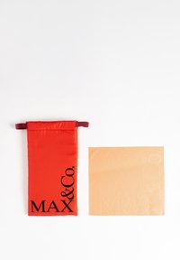 Pungă din țesătură roșie cu litere închise "MAX & Co." și un pătrat bej texturat cu litere embosate. Ambele obiecte au un design minimalist.