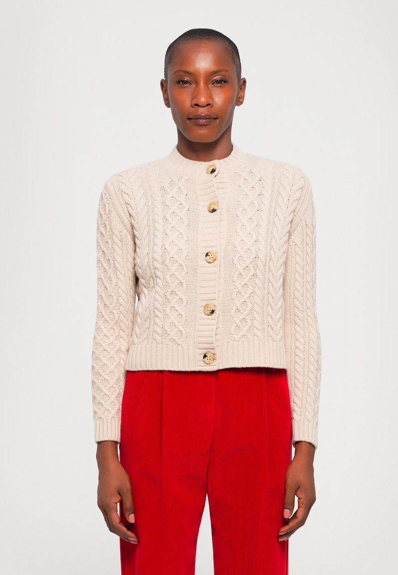 Knit cardigan in beige with cable pattern, round neckline, and five wooden buttons. Paired with red corduroy pants, cropped style.