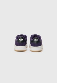 Ljubičaste antilop tenisice s crnim kožnim detaljima, bijelim gumenim potplatom i Adidas logom na peti. Imaju zaobljen vrh i platnene vezice.