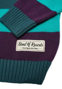 Neulepaita, jossa on teal-, purppura- ja turkoosiraitakohtia. Sisältää ribbauslahkeet ja kangastarran, jossa lukee "Band of Rascals".