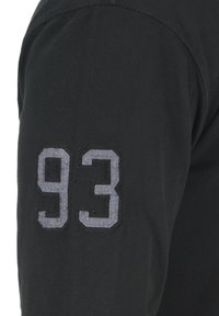 Svart langermet skjorte i strukturert stoff med grå broderte tall "93" på venstre arm, som viser et sporty design.