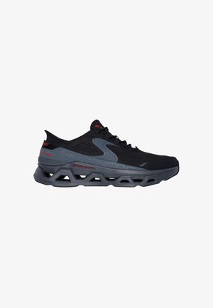 Sneakers da performance neri con una parte superiore testurizzata, accenti grigi e una suola stampata che presenta un design di ventilazione e un marchio rosso.