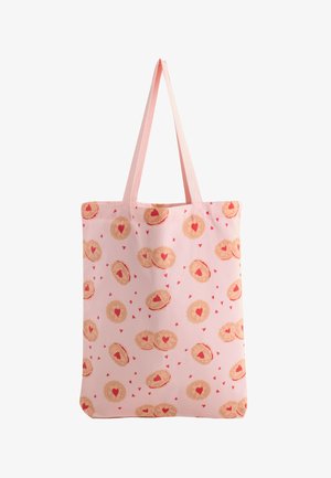 Svetloružová taška s dlhými rúčkami, zdobená vzorom okrúhlych sušienok s červenými srdiečkami v strede a malými rozptýlenými srdiečkami.