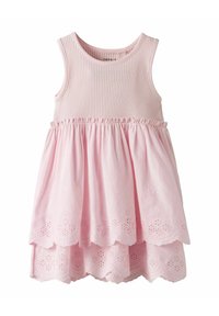 Robe sans manches rose avec un corsage côtelé et une jupe superposée ornée de motifs floraux découpés sur l'ourlet. Tissu doux avec un design fluide.