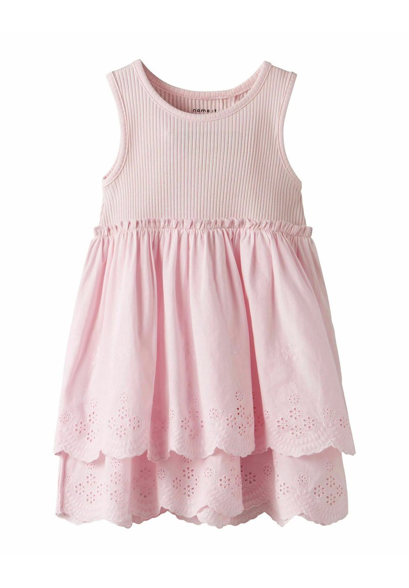 Robe sans manches rose avec un corsage côtelé et une jupe superposée ornée de motifs floraux découpés sur l'ourlet. Tissu doux avec un design fluide.