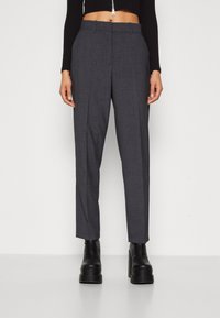 Grå skräddarsydda byxor med rak benmodell, tillverkade av texturerad tyg, med framveck och sidofickor, kombinerade med kraftiga svarta kängor.