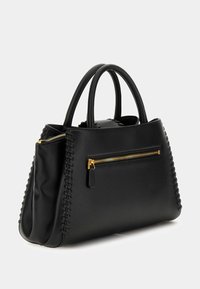 Černá kožená kabelka s dvojitými uchy, viditelná zlatá kapsa na zip vpředu a prošívání podél okrajů, umístěná na jednobarevném pozadí.