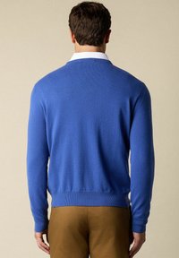 Modrý pletený svetr s kulatým výstřihem, dlouhými rukávy a žebrovanými manžetami. Vyroben z měkkého materiálu, který vykazuje hladkou strukturu.