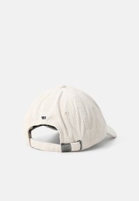 White corduroy cap with a curved brim, featuring a back strap for adjustment and stitched detailing. The back displays the number '85'.