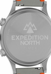 Fond de montre en acier inoxydable avec logo et texte gravés. Doté d'un bracelet gris avec des accents orange. Résistant à l'eau jusqu'à 100 mètres.