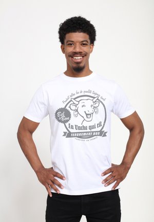 White cotton t-shirt featuring a graphic of a smiling cow with text in gray. Short sleeves and crew neck design.
