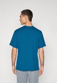 Blå kortærmet t-shirt lavet af blødt stof, med rund halsudskæring og en afslappet pasform. Bagsiden viser et glat, enkelt design.