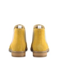 Žluté kotníkové boty z broušené kůže s hladkým béžovým elastickým postranním panelem a světle hnědým nahromaděným podpatkem. Mají prošívaný design a poutko na přetažení.