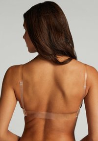 Transparante bh met verstelbare banden, voorzien van een gladde, naadloze uitstraling. Kleur is nude met minimale hardware en een subtiele haaksluiting.