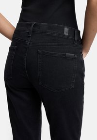 Schwarze Denim-Jeans im Regular Fit, mit mittelhohem Bund und dezenten Nähten. Verfügt über zwei Gesäßtaschen mit einem Logo-Anhänger am Bund.