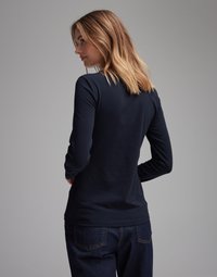 Navy long-sleeve top featuring a fitted design, smooth texture, and round neckline, paired with dark denim jeans.