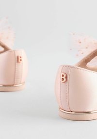 Ballerine rosa pallido con finitura satinata, dettagli metallici e un fiocco in tessuto trasparente sul retro. Logo "B" sul tallone.