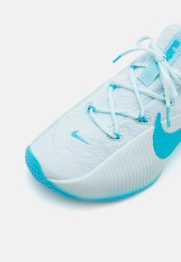 Light blue athletic shoe with a textured upper, sleek design, and prominent Nike Swoosh. Features flat laces and a rubber sole with mesh accents.