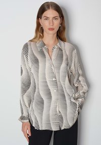 Button-up shirt in lightweight fabric. Abstract black and cream wave pattern, long sleeves, and a classic collar with a button closure.