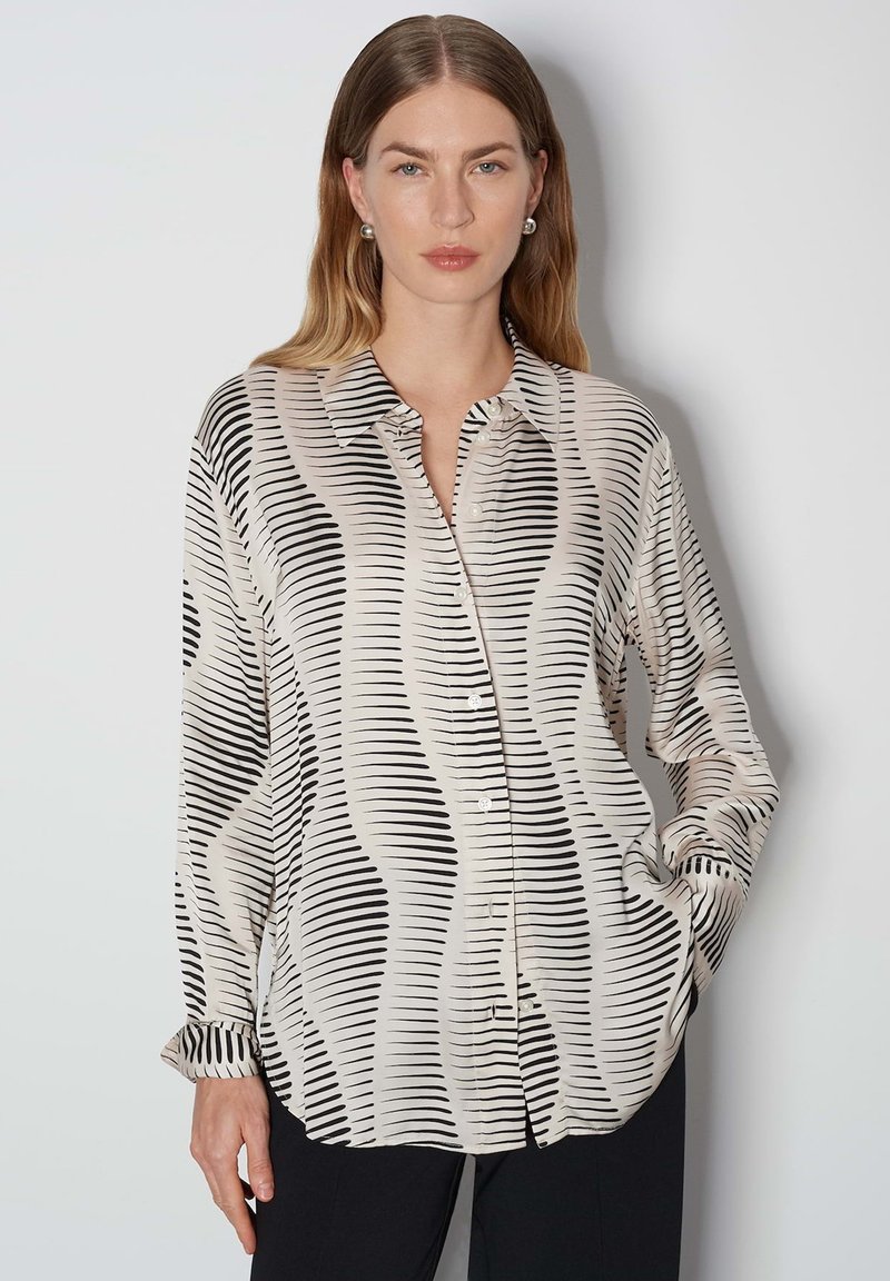 Button-up shirt in lightweight fabric. Abstract black and cream wave pattern, long sleeves, and a classic collar with a button closure.