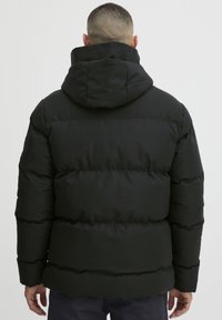 Sort pufferjakke med hætte, der har et quiltet design, elastiske manchetter og en glat udvendig overflade. Ingen synlige logoer eller mønstre.