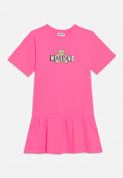 Robe courte à manches courtes rose vif avec ourlet à volants et graphique d'ours en peluche au-dessus du texte blanc et noir "Moschino" sur le devant.
