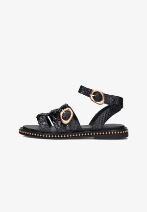 Zwarte sandaal van gestructureerd materiaal, met twee goudkleurige gespaccenten, open ontwerp en een platte zool met decoratieve studs.