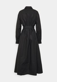 Musta pitkähihainen mekko, jossa kauluksellinen pääntie, vyötärölle solmittava vyö ja liehuva helma. Mekossa on napilliset hihansuut ja yhtenäinen kangas.