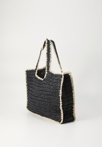 Sac fourre-tout noir tissé avec garniture et poignées crème, forme rectangulaire, debout sur fond blanc uni.