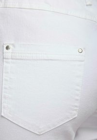 Witte denim jeans met een achterzak met zilveren studs, nette stiksels en een zachte textuur, die eenvoudigheid in ontwerp benadrukt.