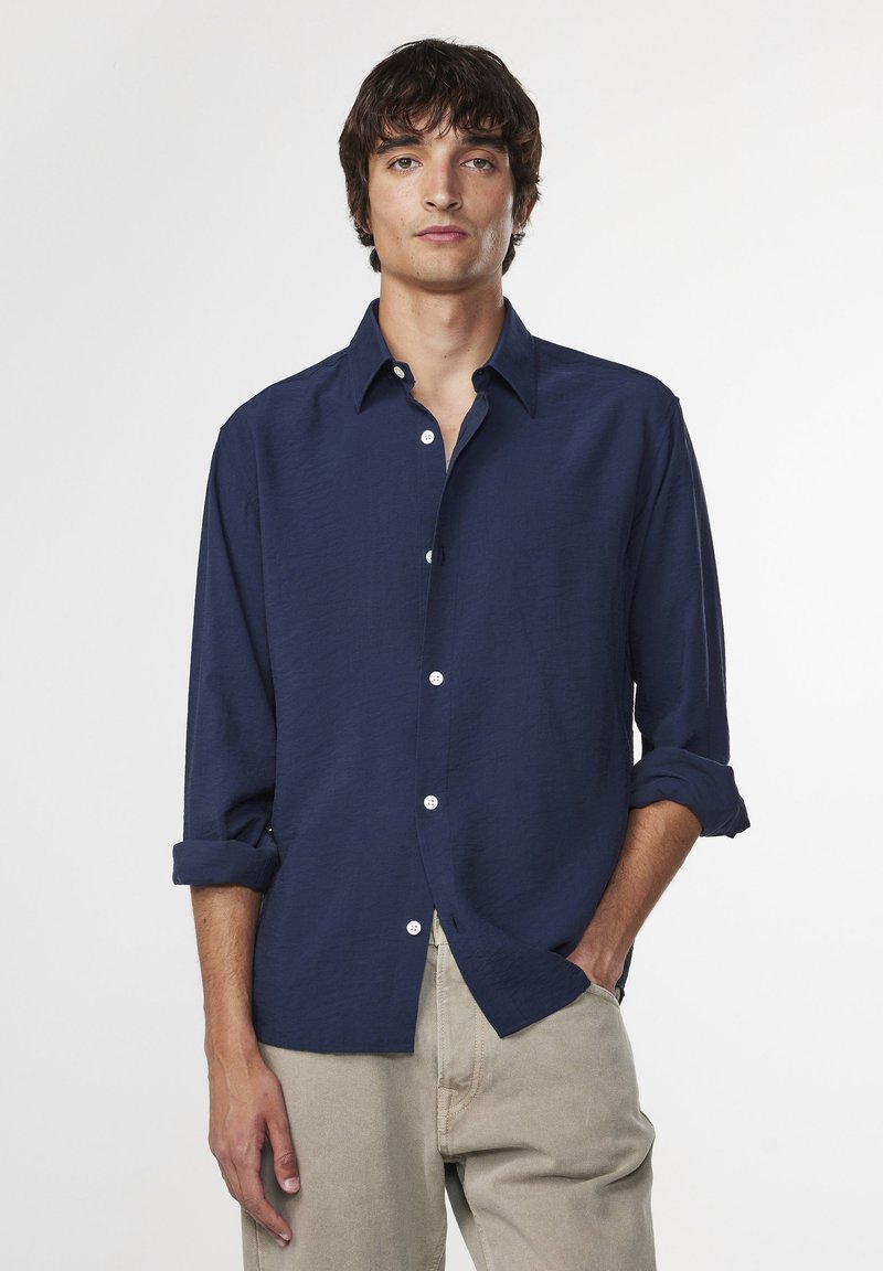 Navy blue long-sleeve shirt made of lightweight fabric, featuring a button-up front, rolled cuffs, and a classic collar.