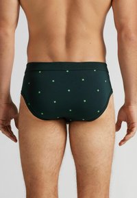 Pánské plavky ve tmavozelené barvě, s jemným vzorem malých světle zelených křížků. Hladká textura, přiléhavý střih a elastický pas.